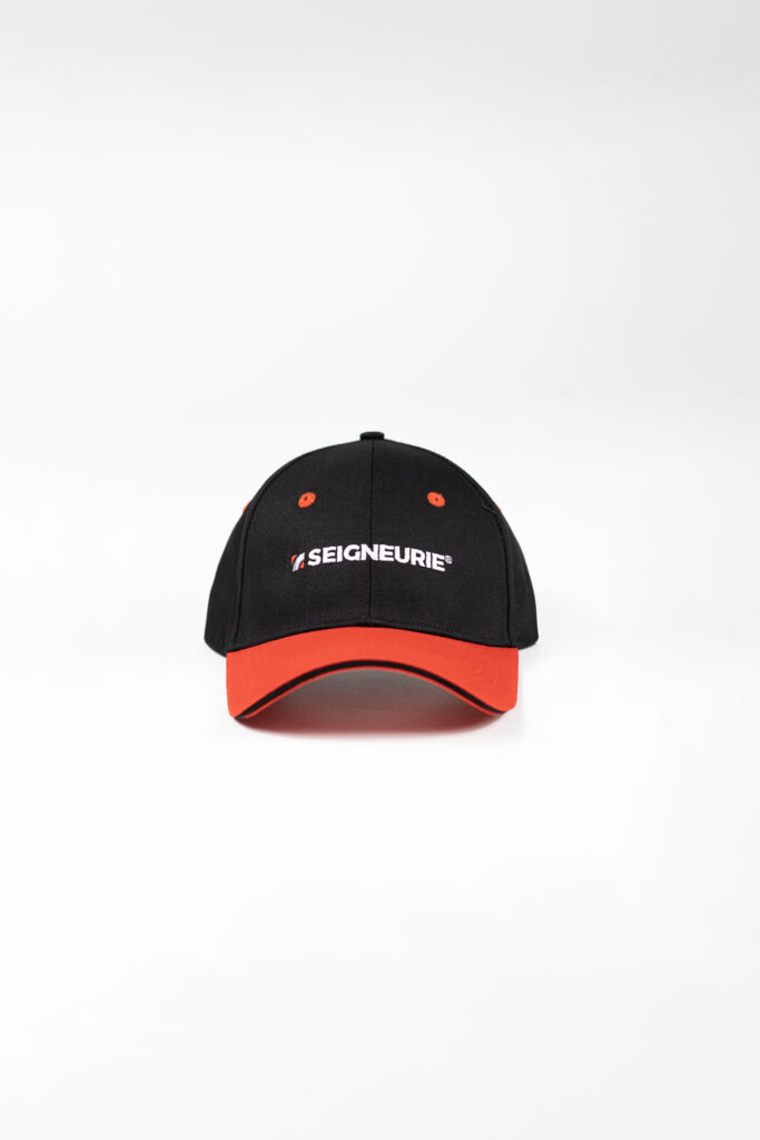 Casquette noire et rouge avec logo Seigneurie brodé en blanc, contraste fort et marquage textile professionnel.