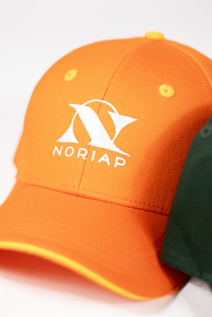 Casquette orange avec logo Noriap brodé en blanc, broderie nette et volume visible sur textile corporate.